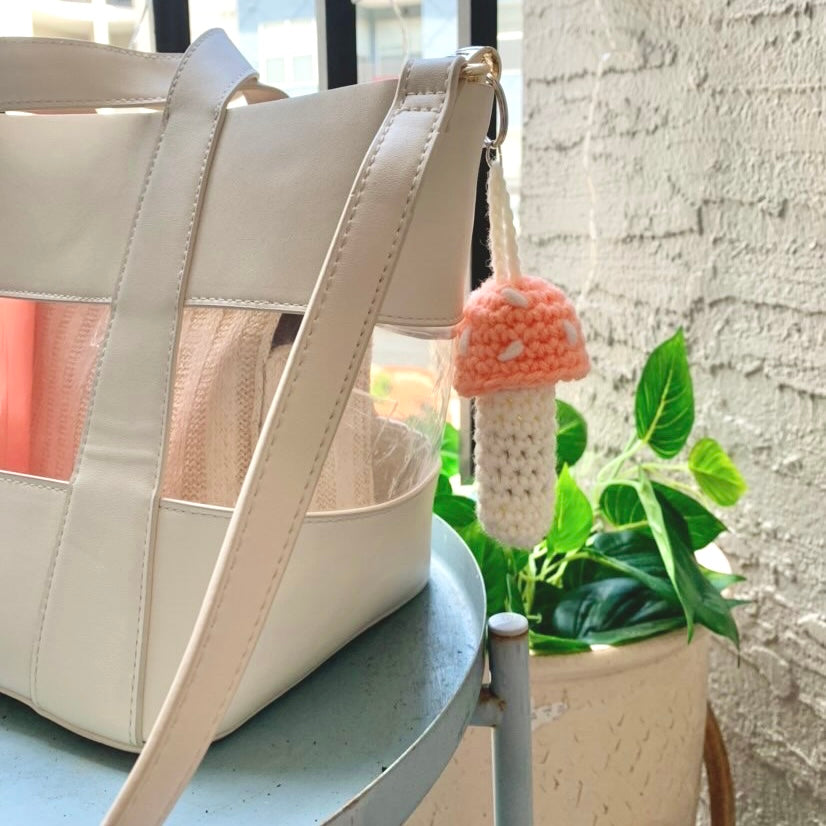 peach and white mushroom keychain attached to a purse/bag