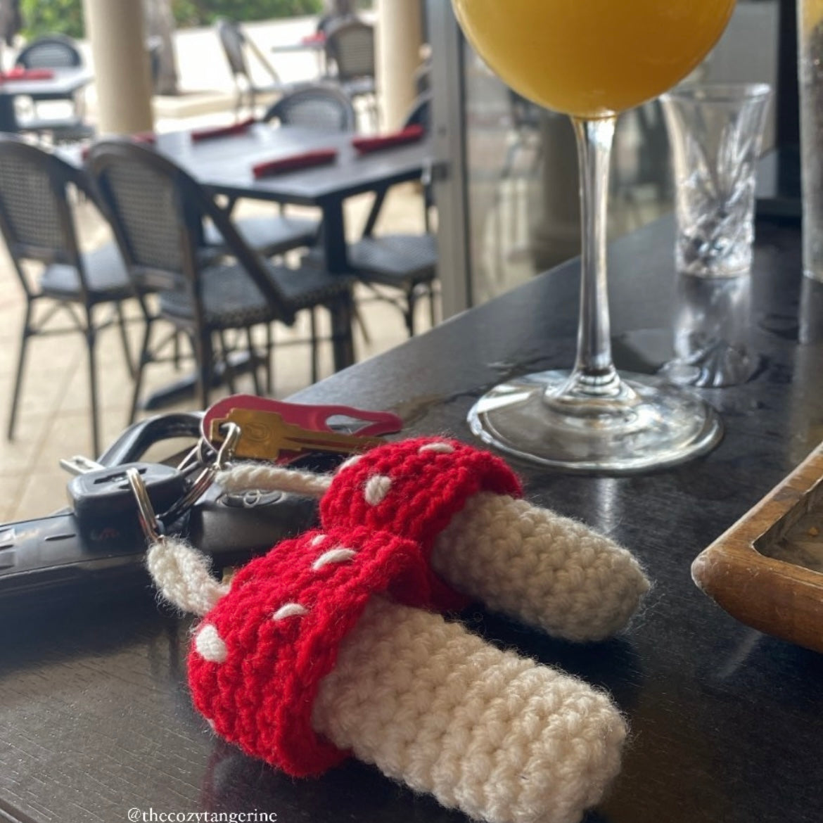 two red and white mushroom crochet keychains that can hold tampons, lighters, Chapstick, lip balm, lip-gloss, money and more