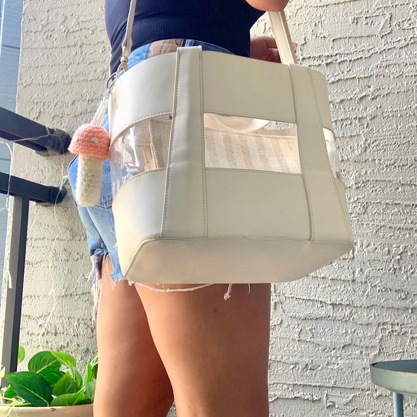 girl wearing a white purse with a peach and white mushroom keychain attached to it